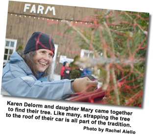 Fallowfield Tree Farm – Christmas Trees – cut-you-own or pre-cut – Photo of Karen Delome who came to Fallowfield Tree Farm with her daughter Mary to find their tree. Like many, strapping the tree to the roof of their car is all part of the tradition.